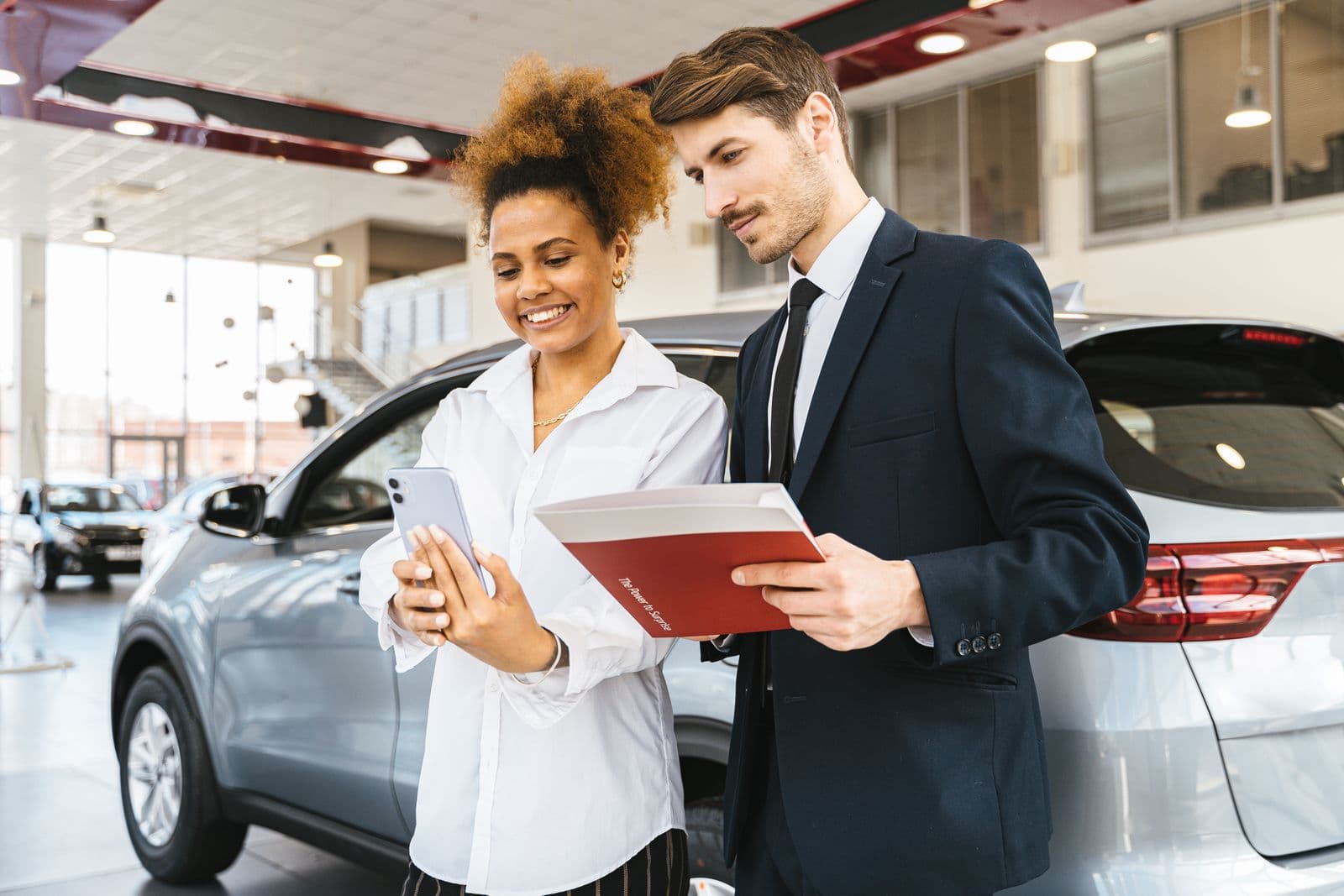 A salesperson and a happy customer going over paperwork in a bright showroom
